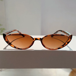 Detailed view of tortoiseshell cat eye frame sunglasses with dark brown lenses on white blocks