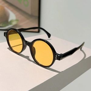 Detail of retro black round frame sunglasses with yellow lenses and silver rivets
