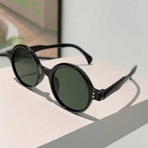 Close-up of retro round black sunglasses with dark green lenses and silver rivet details