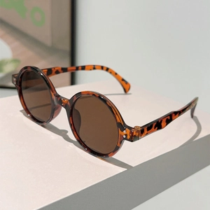 Detail of retro round tortoiseshell sunglasses featuring wavy temples and brown lenses