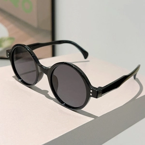 Close-up of retro round black sunglasses with silver rivet detail on the frame