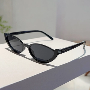 Detailed side view of black cat-eye sunglasses with silver rivets on a white pedestal