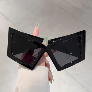 Detail view of bold black X-shaped futuristic sunglasses with thick avant-garde frames