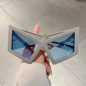 Detail view of futuristic geometric sunglasses with a creamy white frame and blue lenses