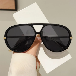 Détail de lunettes aviateur noires avec découpe triangulaire blanche et charnières dorées