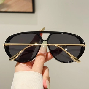 Détail de lunettes aviateur surdimensionnées avec monture noire et fines branches dorées