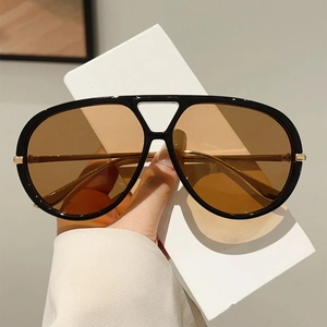 Gros plan de lunettes de soleil aviateur avec verres marrons et branches dorées