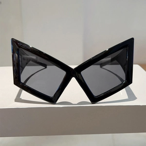 Detail of black geometric butterfly sunglasses with thick frames on a white display stand