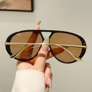 Détail de lunettes aviateur avec verres couleur thé et branches en métal doré