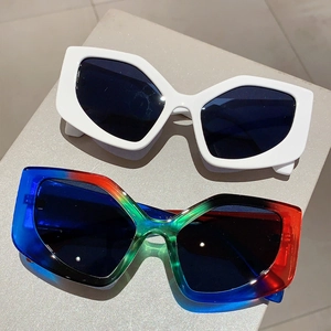 Close-up of white and colorful cat eye sunglasses displayed on a gray pedestal