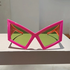 Detail of neon pink geometric X-frame sunglasses with green lenses and orange temples