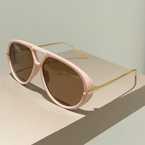 Lunettes aviateur roses avec branches dorées sur support géométrique de style minimaliste