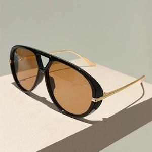 Détail de lunettes aviateur élégantes avec branches dorées et verres teintés ambre