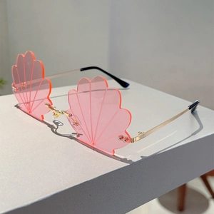 Detail of pink shell-shaped rimless lenses with gold metal frames and textured grooves