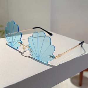Detail view of light blue shell-shaped rimless sunglasses with gold metal temples