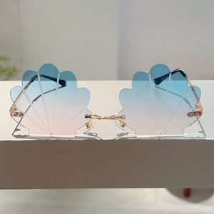 Detail of shell-shaped rimless sunglasses featuring blue-pink gradient lenses and gold metal