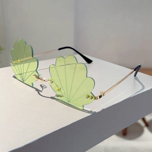 Detail of rimless seashell-shaped sunglasses with light green lenses and gold metal temples