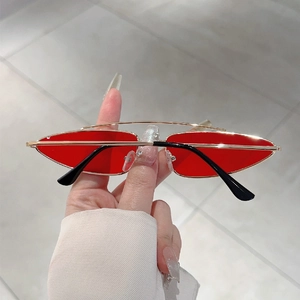 Detail shot of vintage triangle sunglasses with gold metal frame and red lenses