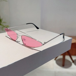 Detailed view of narrow cat-eye sunglasses with silver metal frame and pink lenses