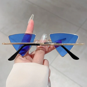 Dettaglio occhiali da sole triangolari con lenti blu e sottile montatura dorata