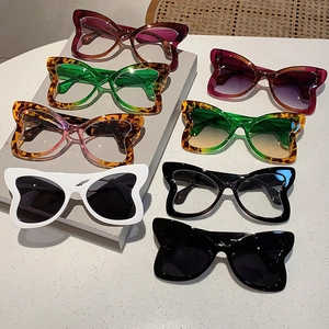 Fashionable oversized butterfly frame sunglasses in various colors on a white marble surface