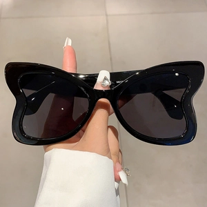 Detail shot of black butterfly shaped sunglasses with unique oversized wing frame design