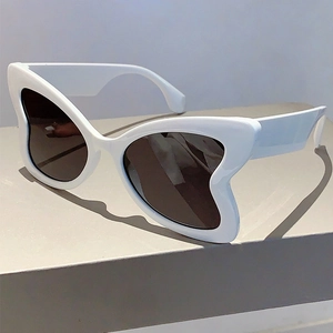 Detail view of bold white butterfly frame sunglasses with dark lenses on display stand