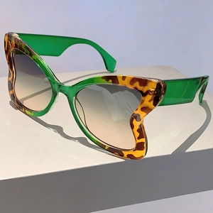 Detail of butterfly-frame sunglasses with green leopard wave edges and gradient lenses