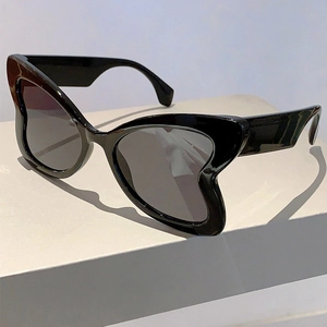 Close-up of black butterfly frame sunglasses on a minimalist white geometric block