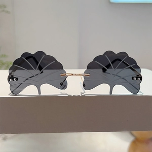 Macro detail of rimless ginkgo leaf sunglasses featuring grey lenses and gold hardware