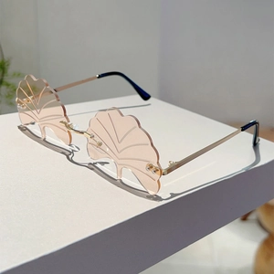 Detail view of pink ginkgo leaf shaped rimless sunglasses with elegant gold metal frame