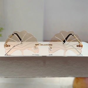 Detailed view of ginkgo leaf shaped rimless sunglasses with gold metal bridge and stems