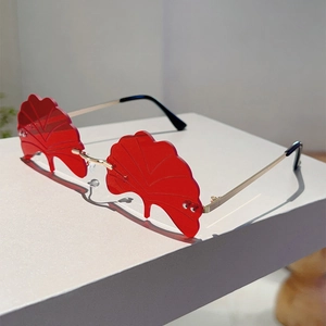 Detailed close-up of red ginkgo leaf shaped rimless sunglasses with gold metal temples