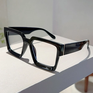 Close-up of thick square frame glasses with polished finish and metal hinge details
