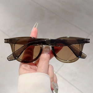 Close-up of translucent olive brown round frame sunglasses with tinted tea lenses