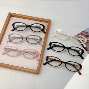 Retro oval anti-blue light glasses frames in multiple colors on a wooden tray