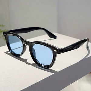 Close-up of retro round frame sunglasses with blue lenses and silver wing-shaped rivets