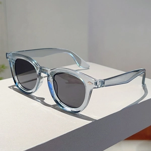 Detail of transparent light blue round sunglasses with silver rivets and grey lenses