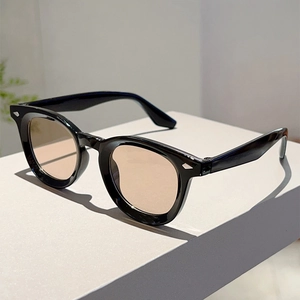 Close-up of retro round black sunglasses with amber lenses and silver rivet accents