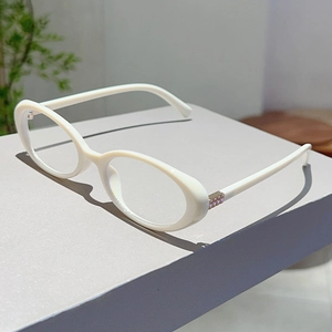 Detail of white oval glasses frame featuring decorative crystal-encrusted side hinges