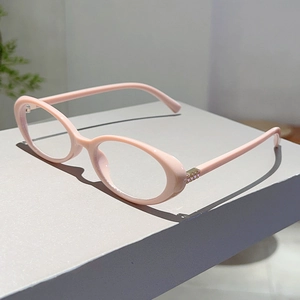 Detail of pink oval glasses frame featuring gold metal hinges with sparkling crystal accents