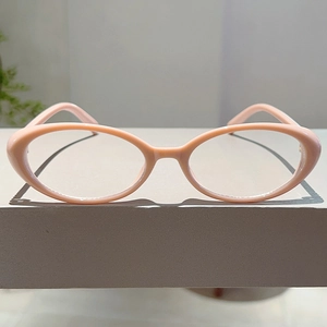 Detailed view of pink cat-eye eyeglass frames made of acetate on a minimalist stand