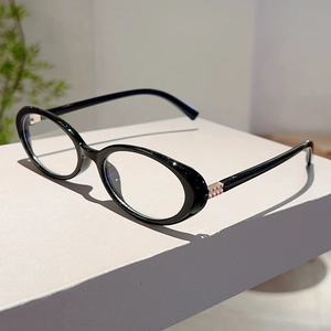 Detail view of oval black eyewear frame with decorative pink and gold rivet accents