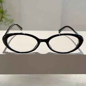 Macro detail of glossy black oval eyeglass frames on white geometric stand