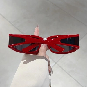 Detail of red Y2K sunglasses featuring a unique X-shaped bridge and futuristic frame design