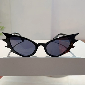 Detail of black batwing frame sunglasses with dark grey lenses on white display