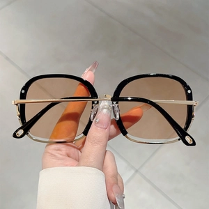 Detail of square black and gold metal sunglasses with light brown gradient lenses