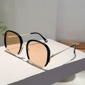 Detail of square metal sunglasses with tea-tinted lenses and gold-black frame details