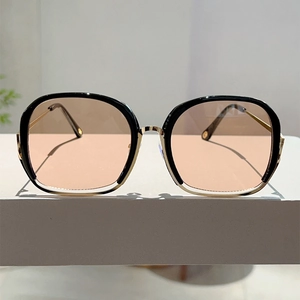 Close-up of square sunglasses featuring black and gold metal frames with gradient lenses
