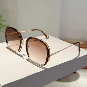 Close-up of tortoise shell and gold metal square frame sunglasses with gradient lenses